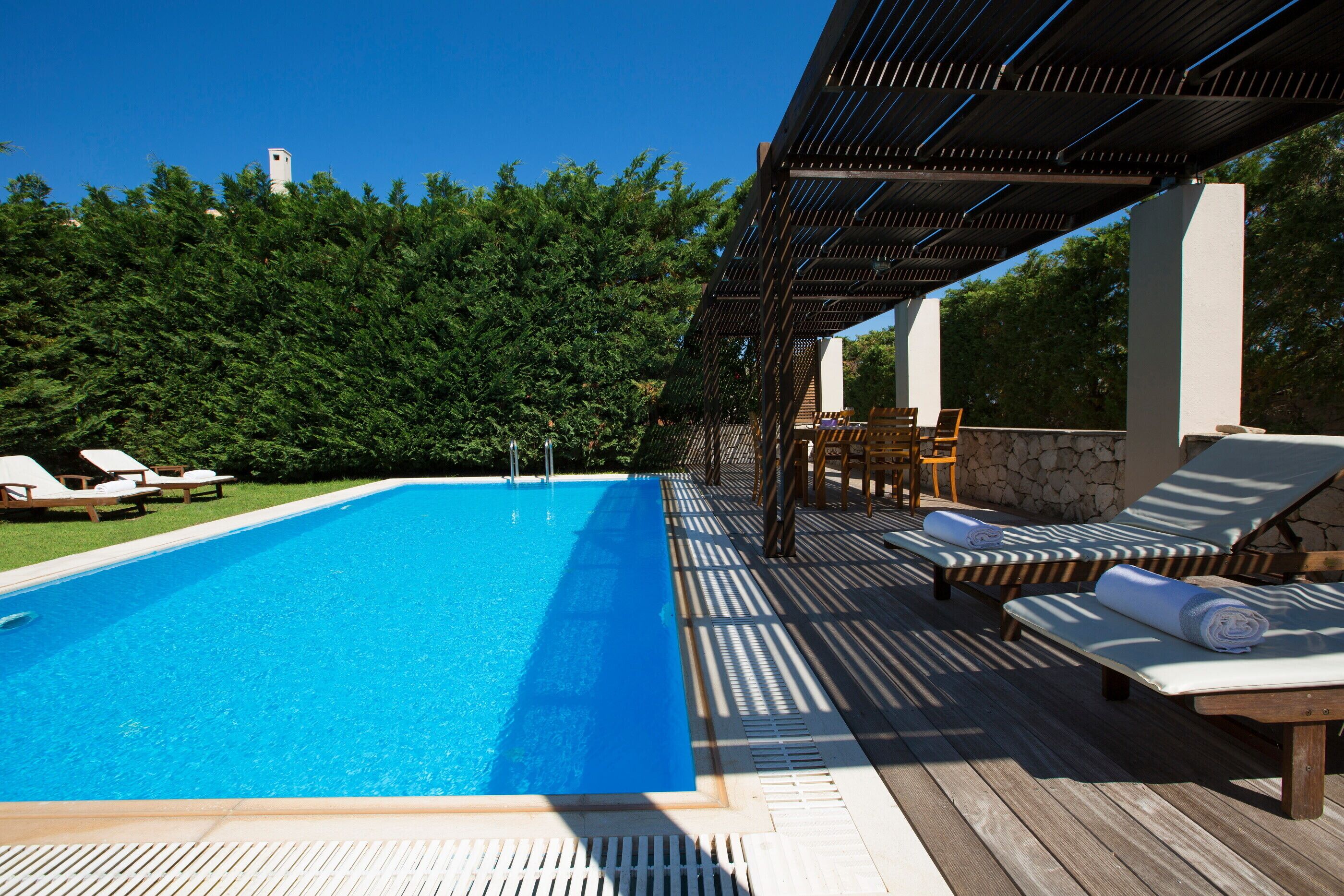 A swimming pool with lounge chairs and a pergola.