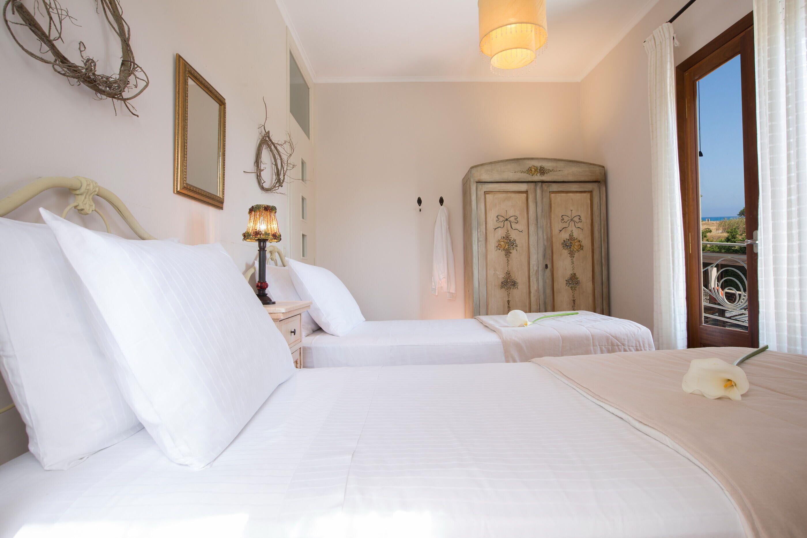 Una camera d'albergo con due letti, un armadio, una lampada e vista sull'esterno.