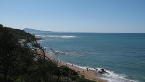 Une plage avec un ciel dégagé, des vagues et des gens.