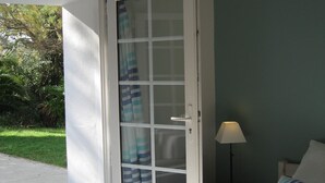 Une chambre à coucher avec un lit, une table de chevet, une lampe et une fenêtre avec des rideaux.