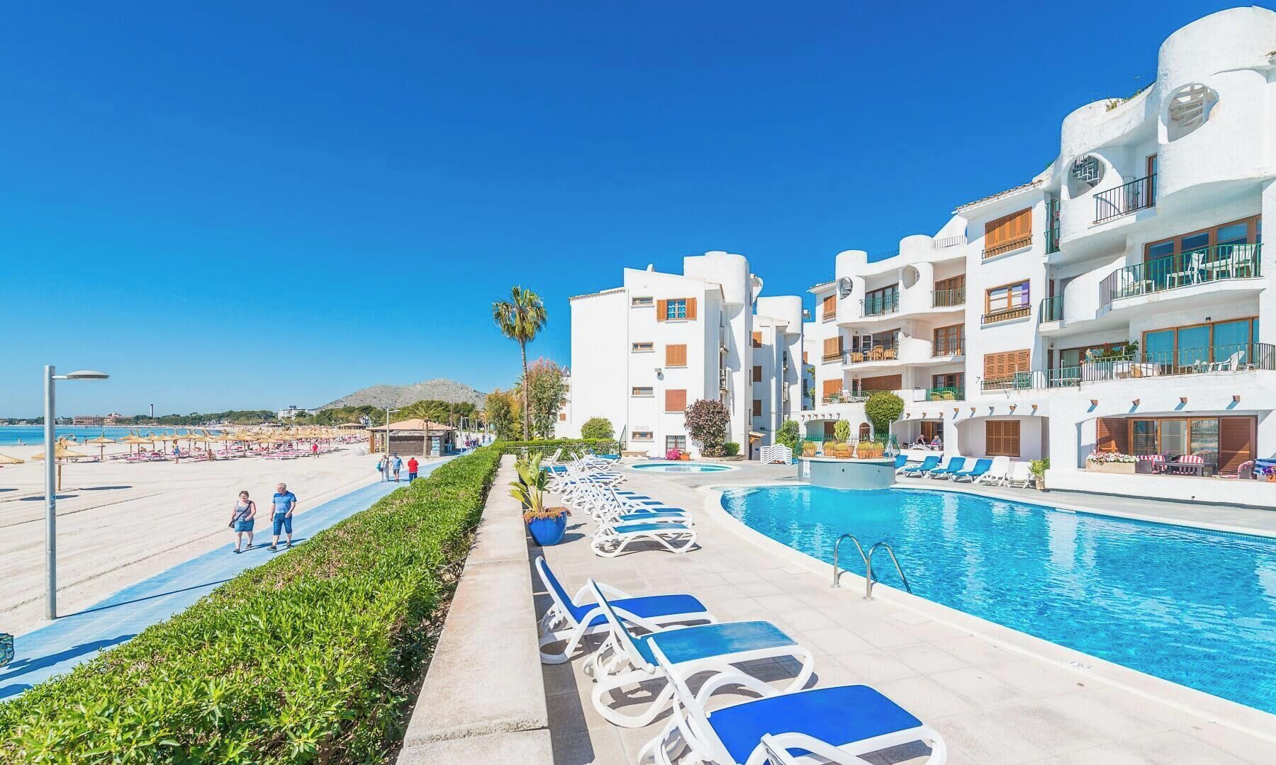 Een resort met een zwembad, ligbedden en een strandgebied.