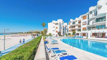 Een resort met een zwembad, ligbedden en een strandgebied.