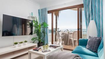 Een moderne woonkamer met een flatscreen televisie, een bank, een salontafel en een balkon met uitzicht op zee.