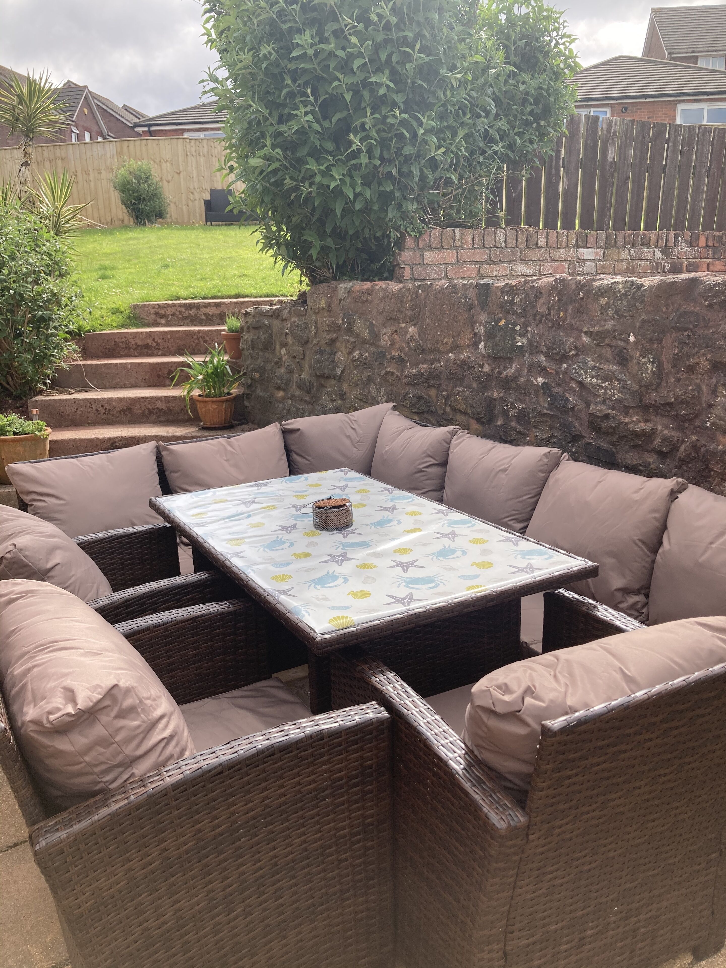 An outdoor patio area with wicker furniture and a table with a patterned tablecloth.