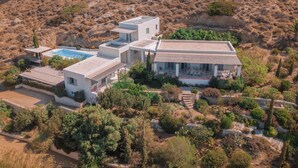 Eine moderne Villa mit Swimmingpool, mehreren Etagen und einem Garten.