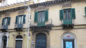 A building with green shutters, a closed door, and a sign for 'Original Marines' with a price list.