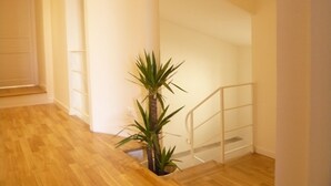 A staircase with a handrail, a wooden floor, and a potted plant.