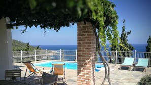 A poolside area with lounge chairs, a table, and a view of the sea. -  Pool Villa Perivoliou walking distance to 4 beaches, near Mamma Mia Church (Northern Sporades)