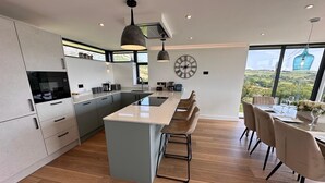 Una cocina moderna con una isla central, un comedor con vistas y un ventanal grande.