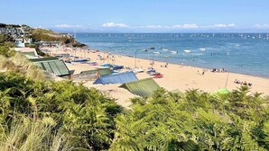 Una playa con barcos, sombrillas y gente.