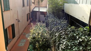 A narrow alleyway with a small garden area, a tree, and a building with shutters. - Completely renovated apartment in the center (Ravenna)