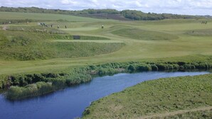 Camp de golf amb una bassa d'aigua i turons verds ondulats.