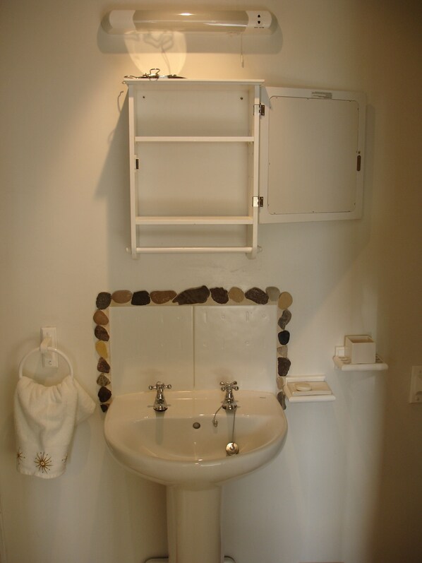 A bathroom with a white sink, two faucets, a mirror, and a medicine cabinet. - Causeway Cottage Portballintrae. Beautiful Country Views, minutes from the sea (Bushmills)