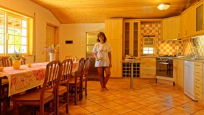 Une cuisine avec des meubles de rangement en bois, un sol carrelé, une table à manger avec des chaises et un réfrigérateur.