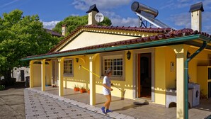 Un bâtiment jaune avec un toit recouvert de tuiles, une antenne parabolique et une autre antenne parabolique sur le toit.