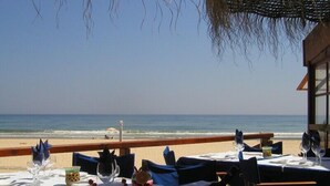 Un restaurante frente a la playa con mesas dispuestas para comer, con vista al océano.