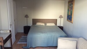 Una camera da letto con un letto, due comodini, una poltrona, un divano e un quadro appeso al muro.