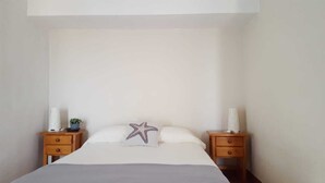 A bedroom with a bed, two nightstands, a star-shaped pillow, and a small plant on one nightstand. - OFFER season 2025. Spectacular ocean and cliff views (Puerto Santiago. Los Gigantes)