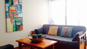 A living room with a sofa, a coffee table, and a painting on the wall. - OFFER season 2025. Spectacular ocean and cliff views (Puerto Santiago. Los Gigantes)