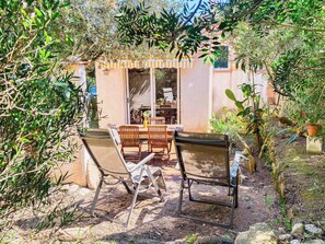 Une terrasse avec mobilier d’extérieur, une porte-fenêtre coulissante et une vue sur le jardin environnant.