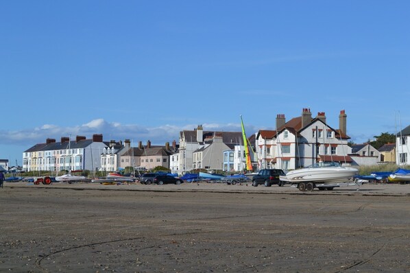 Une propriété située en bord de mer, avec une rangée de maisons colorées, une plage de sable et des bateaux.