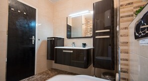 A modern bathroom with a dark vanity, a white sink, and a mirror above it.