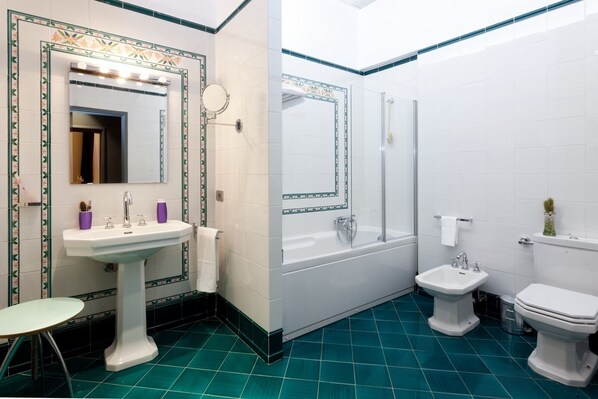 Un baño con lavamanos pedestal, un espejo redondo, una bañera, una ducha, un inodoro y un bidé.