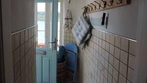 A bathroom with a blue door, a wicker basket, a blue chair, and a towel rack with towels. - Runswick Bay Top Gallant Cottage - outside seating  - sea and beach views (Runswick Bay)