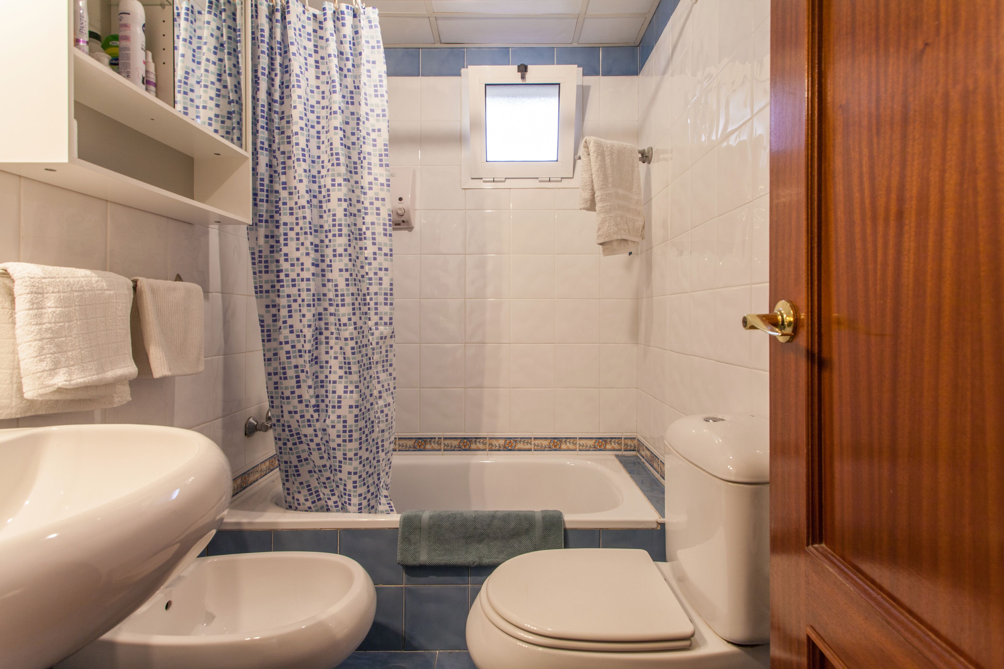 Un baño con bañera, dos inodoros, lavamanos y cortina de ducha.