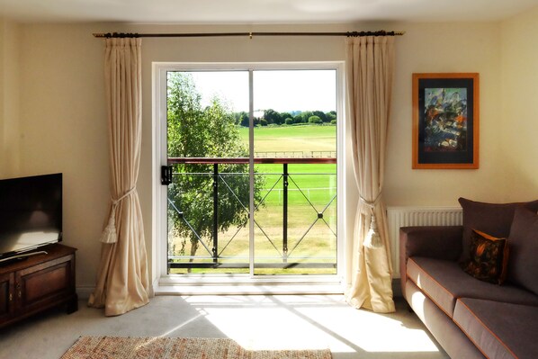 A living room with a large window, a sofa, a TV, and a painting on the wall. - Sleeps 6, Parking, Great View. 3 Bedrooms, 4 beds, easy walk to town centry (Stratford Upon Avon)