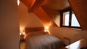 A bedroom with a sloped ceiling, a bed, bedside lamps, a desk, and a window. - Chalet for 6 people in Cauterets with free parking space (Cauterets)