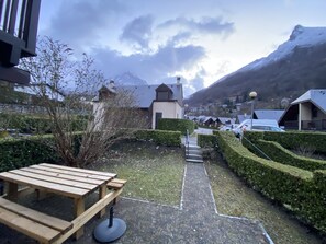 A courtyard with a wooden picnic table, neatly trimmed hedges, and a pathway leading to a mountain backdrop. - Chalet for 6 people in Cauterets with free parking space (Cauterets)