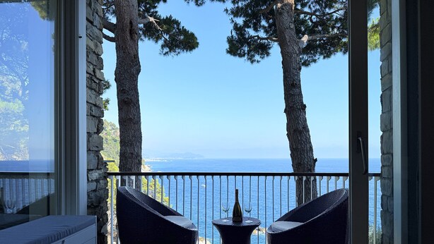 A balcony with wicker furniture and a view of the sea.