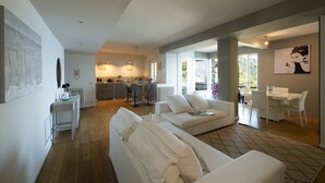 A spacious living area with a sofa, dining table, and kitchen in the background.