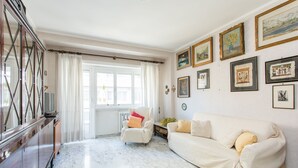 Un salón amplio con un sofá blanco, un armario de madera y una silla.