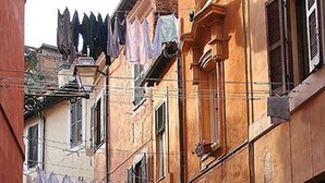Una estrecha calle empedrada con edificios a ambos lados, con puertas en arco y balcones con ropa tendida.