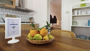 Une cuisine avec un mur recouvert de carreaux, une cuisinière et un panier de fruits sur la table.