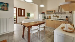 Une cuisine moderne avec des appareils électroménagers blancs, une table à manger en bois et un plan de travail blanc.