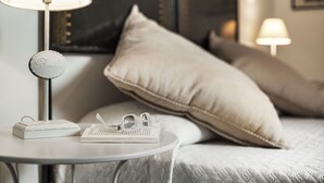 Une chambre à coucher bien rangée, avec une table de chevet, une lampe, un livre et un oreiller.