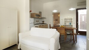 Un espace de vie compact comprenant une kitchenette, un coin repas et un canapé.