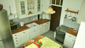 Una cocina compacta con gabinetes blancos, encimera de madera, un fregadero, una estufa y una mesa de comedor con mantel amarillo.