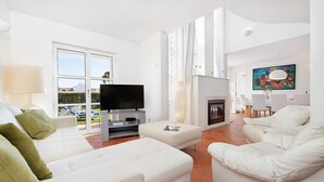 En moderne stue med en hvid sofa, et fladskærms-tv og en pejs.