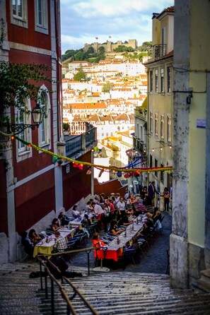 A narrow street with outdoor seating, a staircase, and buildings with balconies. - Between the Carmo and the Trinity (Lisboa)