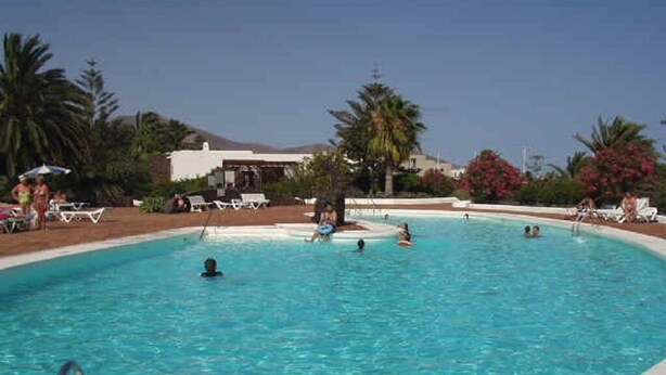 A swimming pool with people swimming and lounging. - Villa 1A on the complex of Casas del Sol  (Playa Blanca)