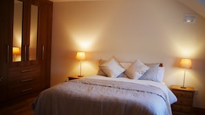 Ein Schlafzimmer mit einem Bett, zwei Nachttischlampen, einem Holzschrank und einer Deckenleuchte.