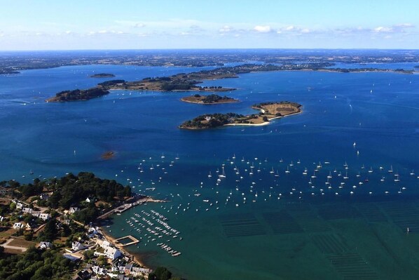 An aerial view of a coastal area with multiple islands, a marina with numerous boats, and residential buildings along the shore.