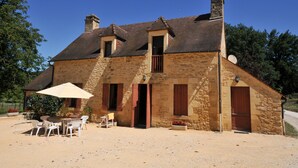 A stone house with a sloped roof, a small porch with chairs, and a table. - Very good location! Character house with private access to the river  (Vitrac)