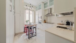 Una cocina moderna con armarios blancos, una campana extractora de acero inoxidable y un lavamanos doble.