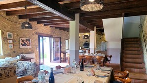 A dining area with a long table set for a meal, wooden chairs, and a stone wall in the background. - Rural house in Girona. 11 bedrooms, up to 30 people, private pool. (Cabanelles)