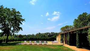 A pool area with lounge chairs and a pergola structure. - Rural house in Girona. 11 bedrooms, up to 30 people, private pool. (Cabanelles)